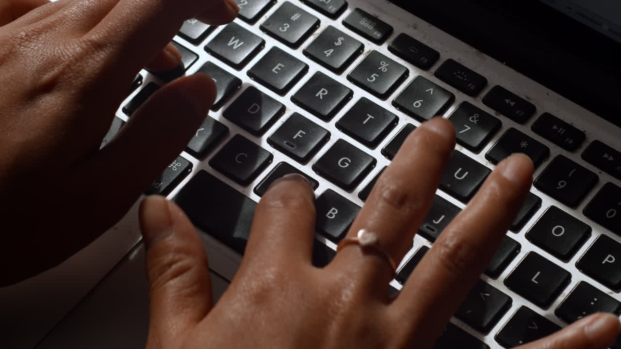 A tight angle of an asian woman typing on a computer laptop keyboard