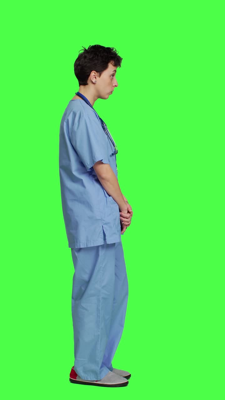 Ritratto di profilo di un'assistente medico sicura di sé che posa con le braccia incrociate in studio