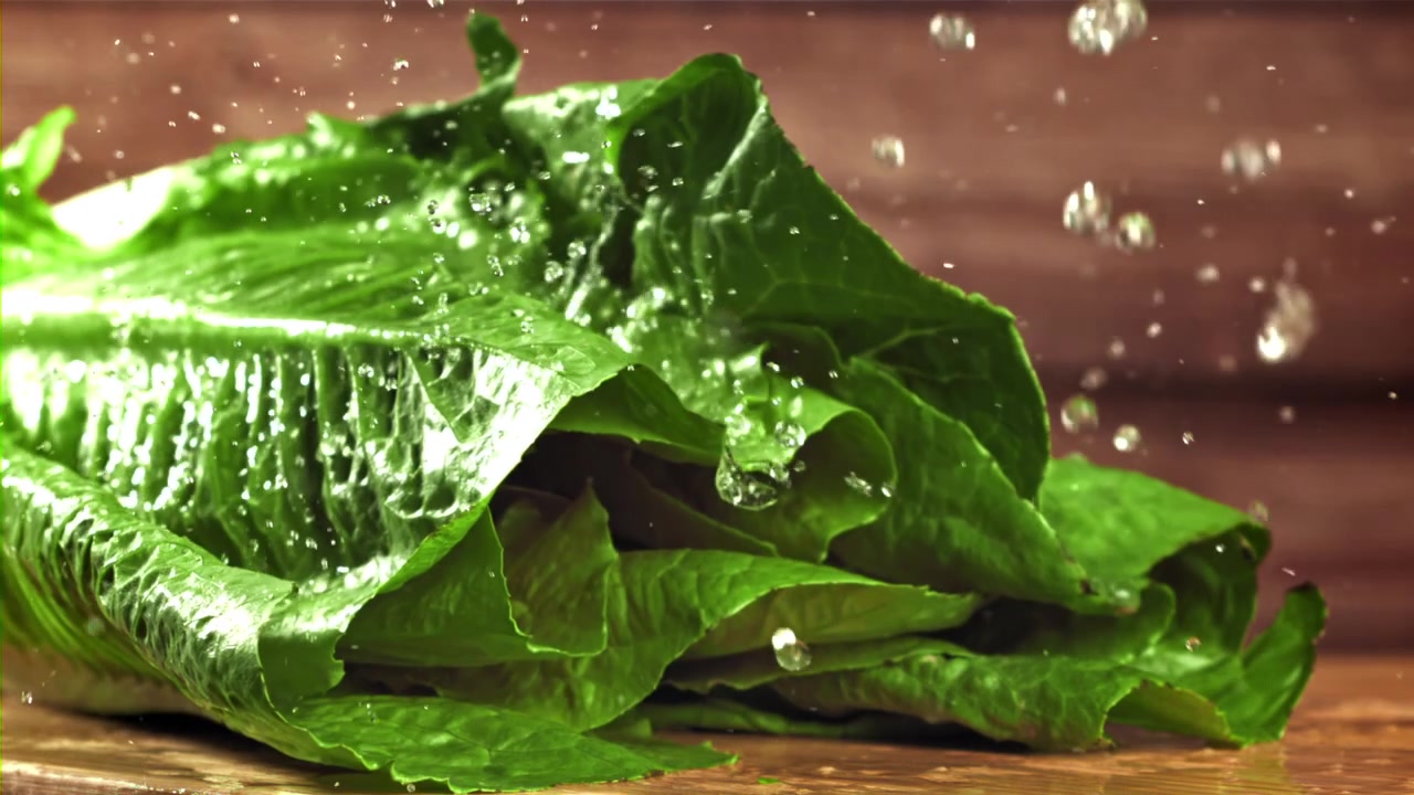 Acqua che schizza al rallentatore su lattuga romana verde fresca
