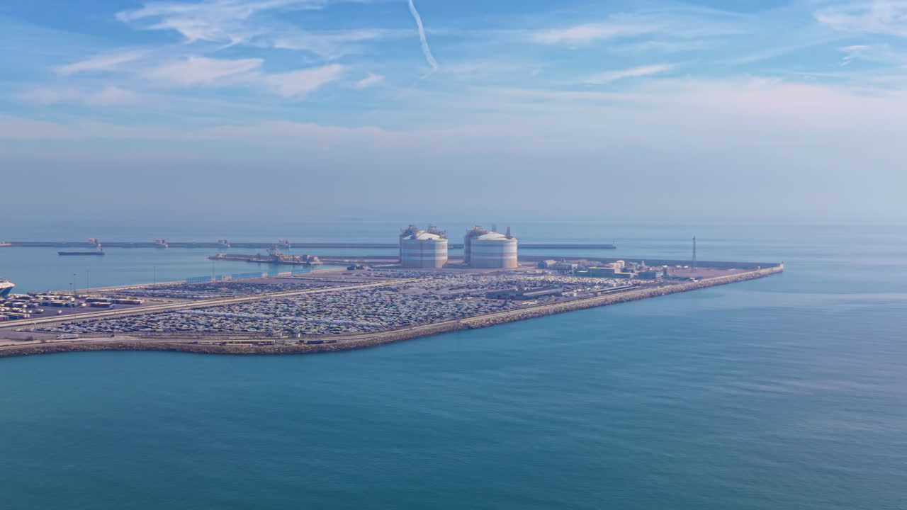 Luftfoto av Sagunt havn med bulklagertanker, logistikkområde for kjøretøy og molo, som illustrerer maritime terminaloperasjoner, infrastruktur for godshåndtering og kystfartøyaktivitet.