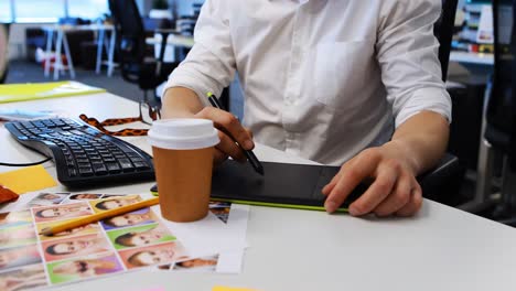 Male-graphic-designer-working-on-graphic-tablet-at-desk