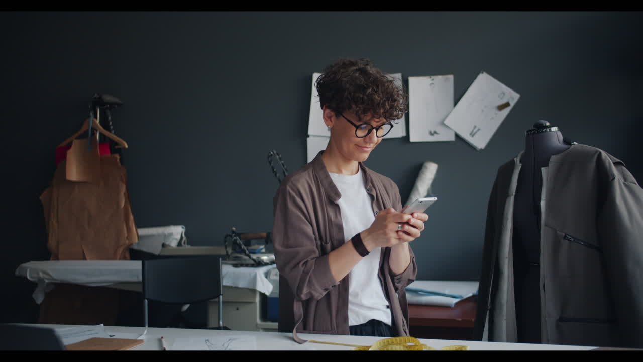 Fashion Designer Using Mobile Phone in Design Studio