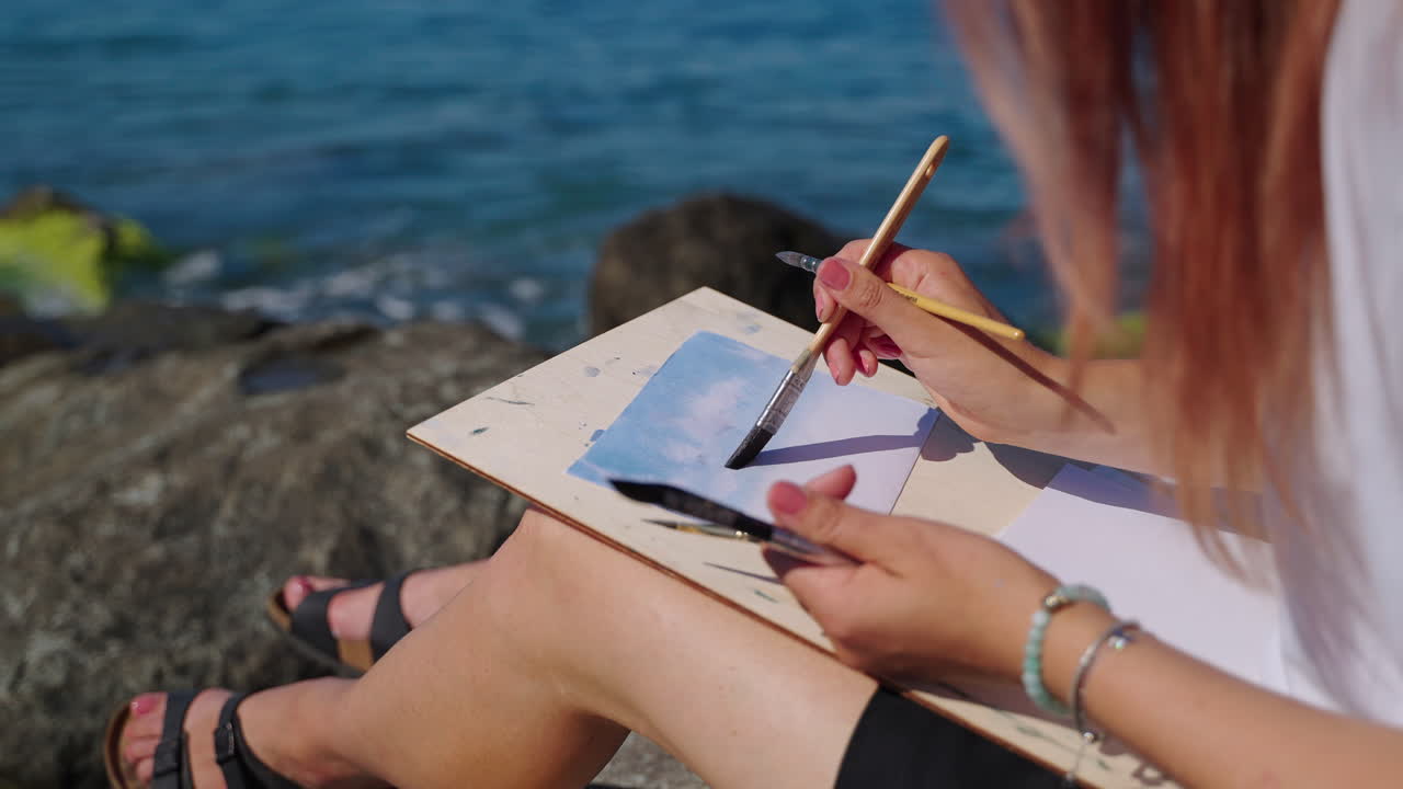 mujer pintando al aire libre junto al mar