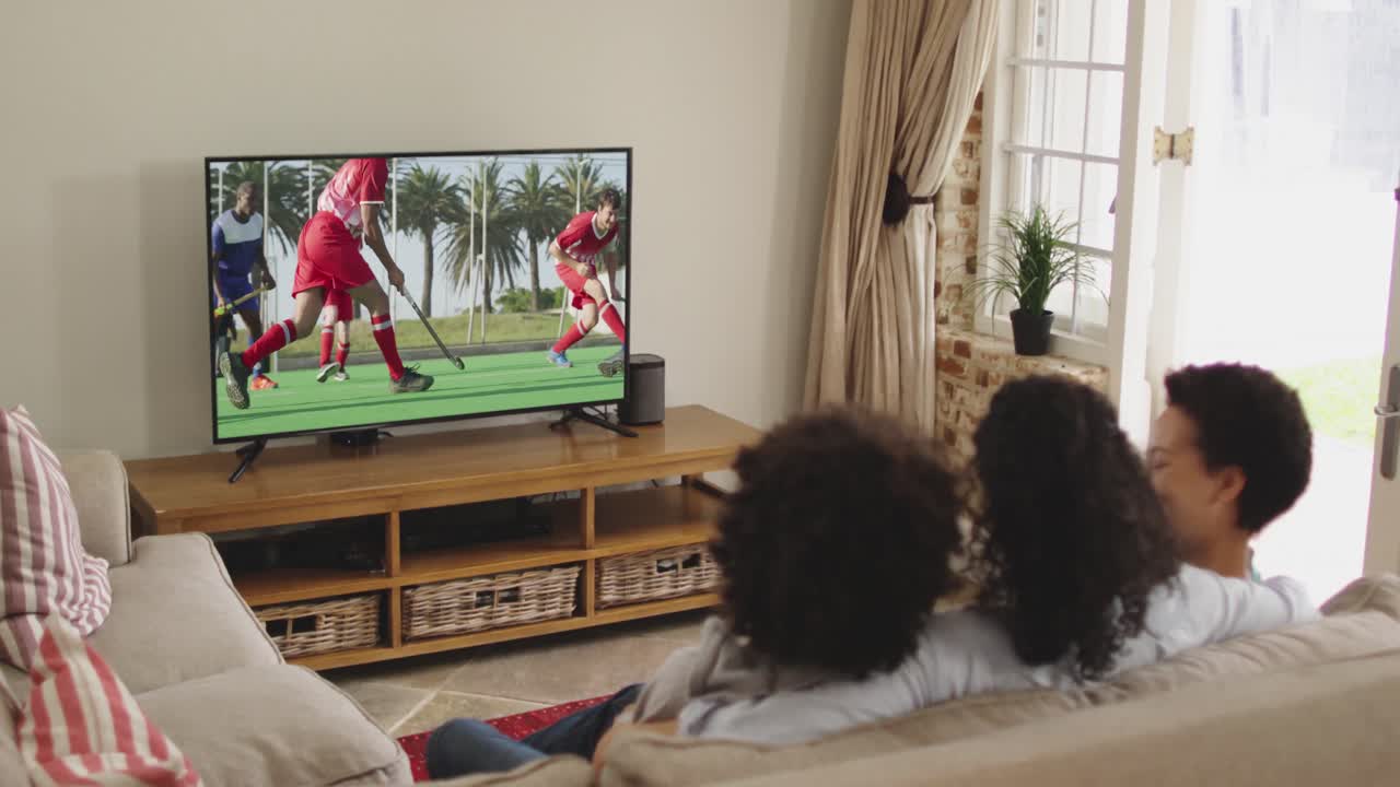 Famiglia felice seduta a casa insieme che guarda una partita di hockey in TV