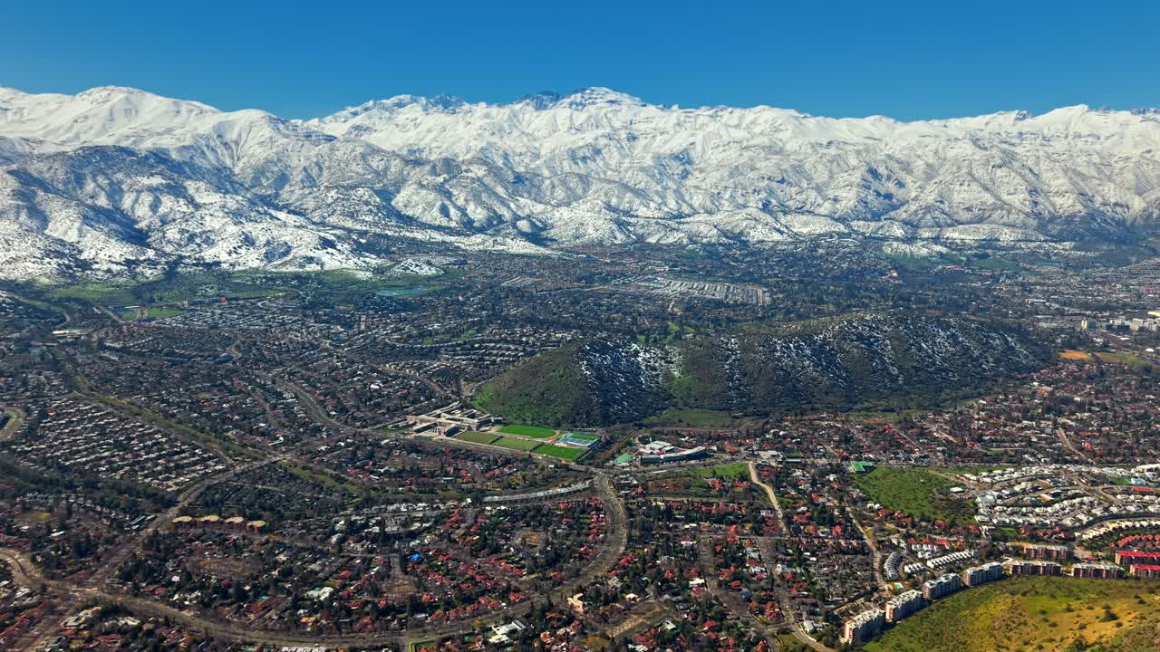 Aerial establishing drone fly Lo Barnechea neighborhood in Santiago de Chile City with El Plomo Snowy Andean Mountain Background