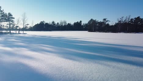 aerial view of snowy bog landscape with frozen lakes in sunny winter day, dunika peat bog , wide angle drone shot moving forward low to the ground