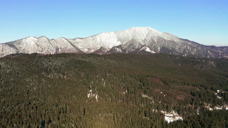 left to right aerial tracking shot of snowy postavarul massif, romania