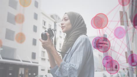 Animation-of-a-network-of-pink-and-red-icons-with-woman-wearing-hijab-taking-photos-in-street