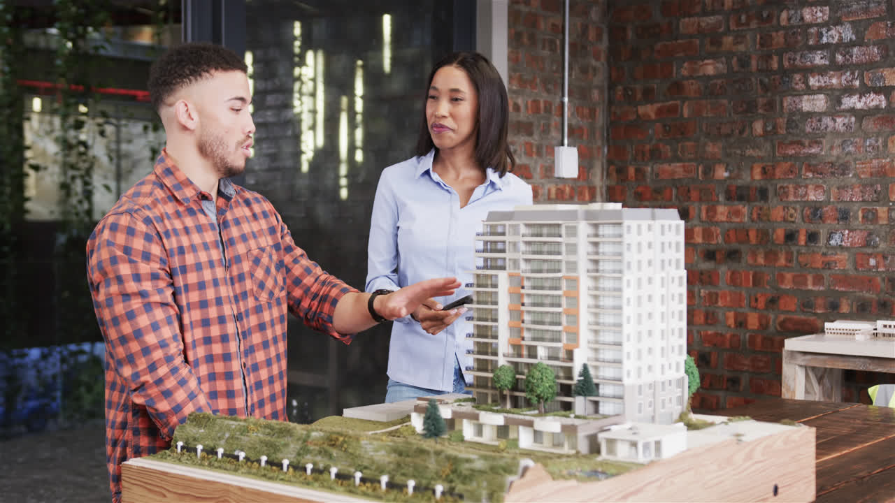 Diverse male and female architect discussing architectural model, slow motion