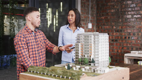 diverse male and female architect discussing architectural model, slow motion