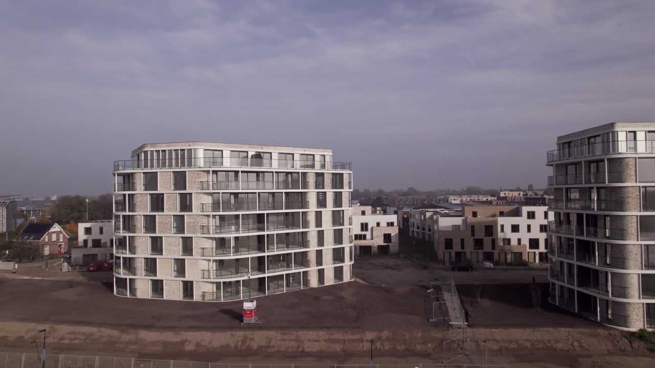 Sideways aerial pan showing exterior facades of newly build luxury apartment towers Pracht along riverside of river IJssel seen from above