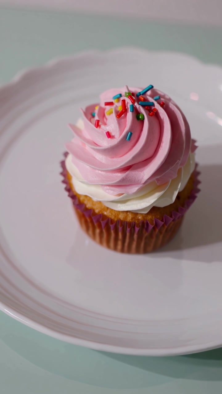 Cupcake singolo con glassa rosa e bianca su un piatto bianco