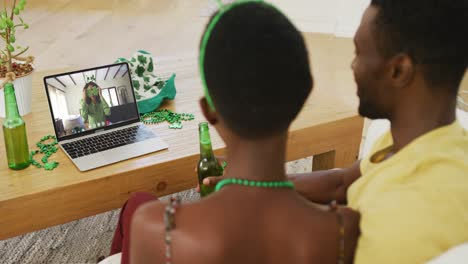 pareja afroamericana en una llamada de video portátil celebrando el día de san patricio con amigos