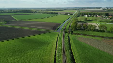 Siguiendo-Una-Vía-De-Tren-En-Un-Paisaje-De-Pólder-Holandés-Con-Un-Dron