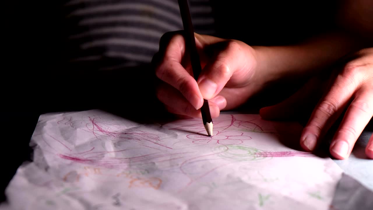 한 여성이 아이에게 종이 한 장에 연필로 꽃을 그리는 방법을 보여줍니다.