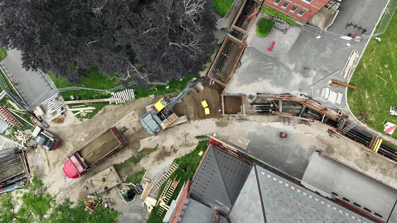 Autonomous construction robot compacting dirt on construction site. Aerial top down landing shot. Modern Construction site in housing area of town.