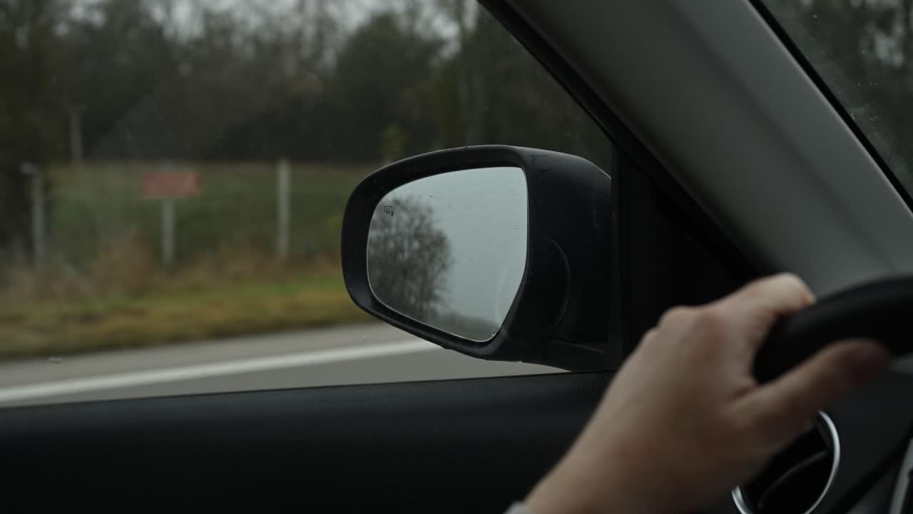 Paesaggio autunnale nebbioso visto attraverso lo specchietto laterale di un'auto durante un viaggio in campagna. Messa a fuoco selettiva