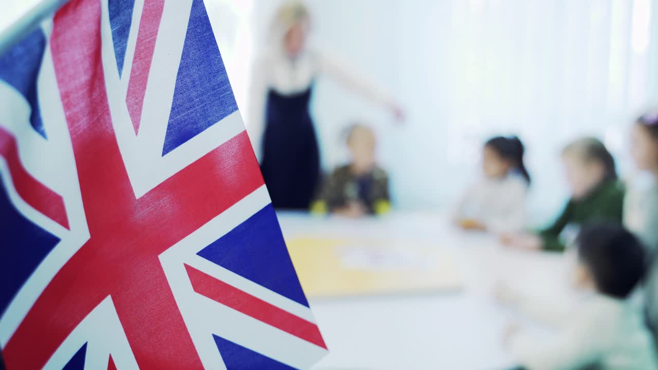 learning English in elementary school. Flag of Great Britain against the background of children with a teacher
