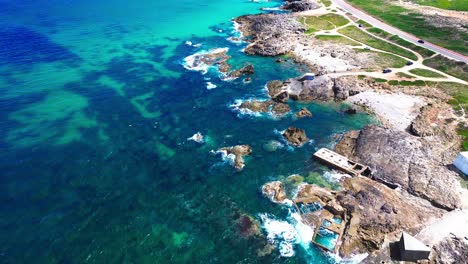 aerial-view-of-blue-ocean,-crashing-waves,-rugged-coastline,-4k