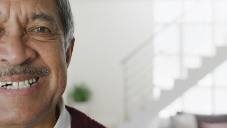 Vídeo-De-Primer-Plano-Retrato-De-Un-Hombre-Birracial-Mayor-En-La-Sala-De-Estar-Sonriendo-A-La-Cámara,-Con-Espacio-Para-Copiar