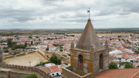 Aerial-orbiting-of-Church-of-Lady-of-Candeias-tower-in-the-Mourão-Castle,-white-houses-Village-in-Background