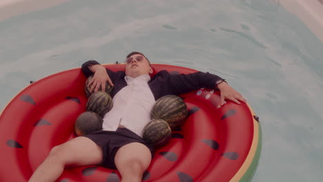 man relaxing in a pool with watermelons