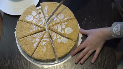 a child, a little girl, cuts into pieces a beautiful homemade yellow cake with a white rose pattern, which stands on a black table. a holiday during quarantine. close-up. top view. faceless. 4k.