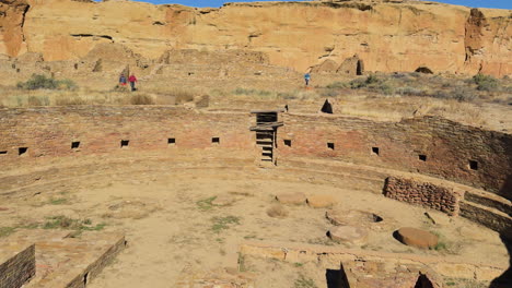 wide view of circular kiva ruins where foreign visitors walking around in desert terrain at chaco canyon, new mexico.