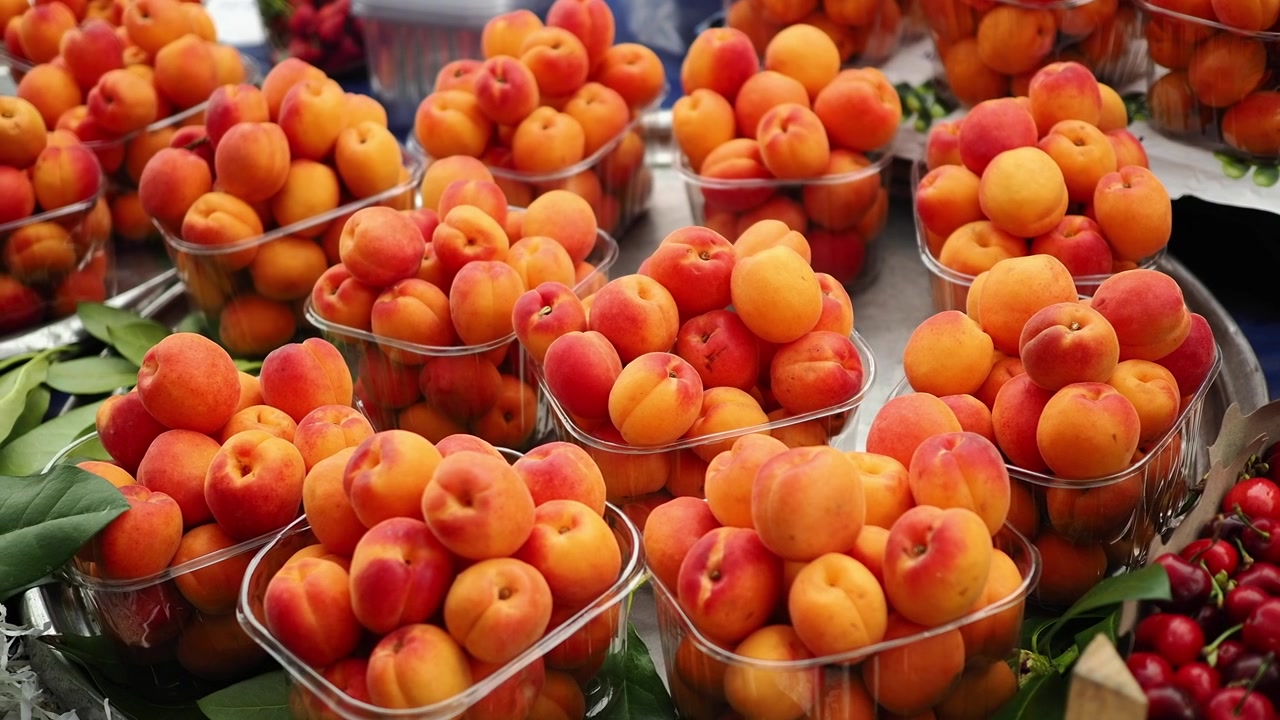 Abricots frais dans des barquettes en plastique sur un étal de marché