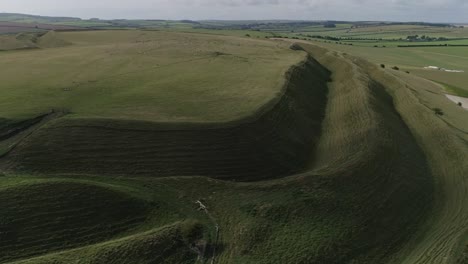 Aerial-tracking-around-the-edge-of-Maiden-Castle,-an-Iron-age-hill-fort