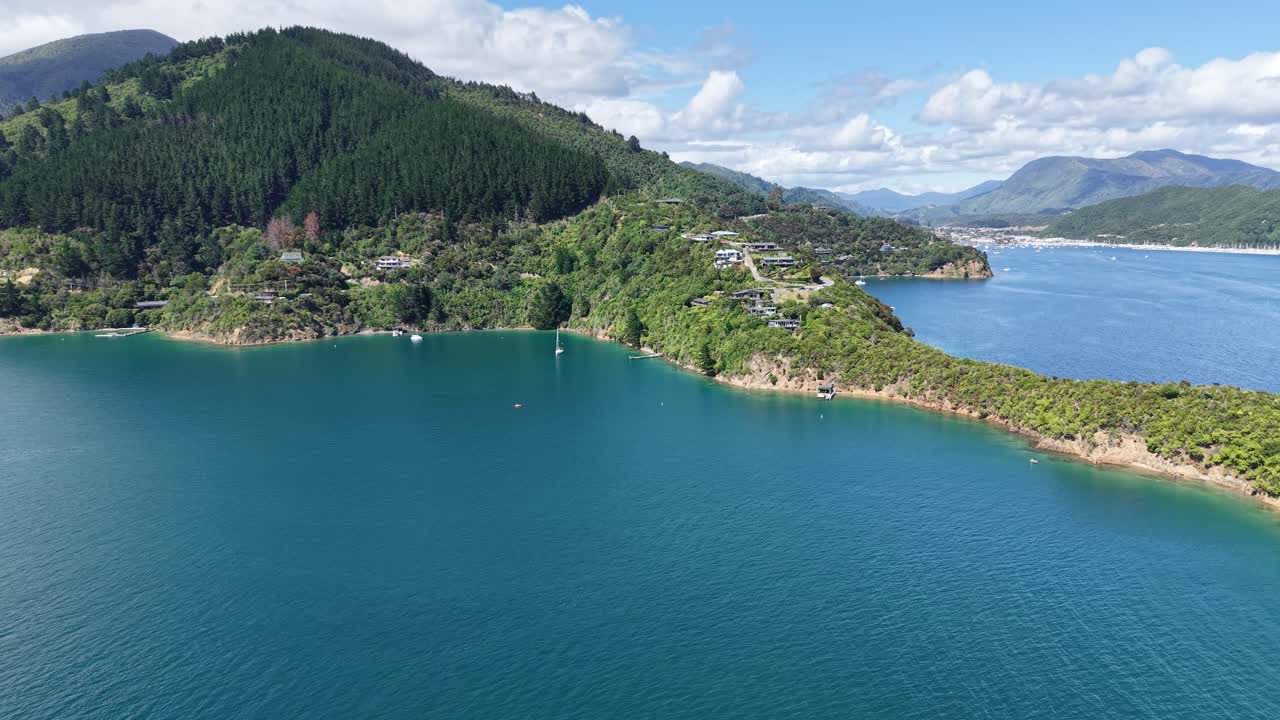 Hidas laskeutuminen kohti kaunista turkoosia vettä, jossa heijastuvat vihreän sävyt alkuperäisestä pensaikosta ja mäntymetsästä (Karaka Point, Queen Charlotte Sound, Uusi-Seelanti).