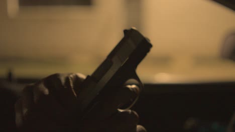 a black man with a hundgun ejects the bullet from his gun close up