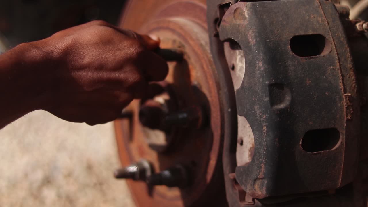 Close up of a hand placing a lug nut on the wheel rotor of a car in maintenance