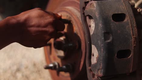 close up of a hand placing a lug nut on the wheel rotor of a car in maintenance
