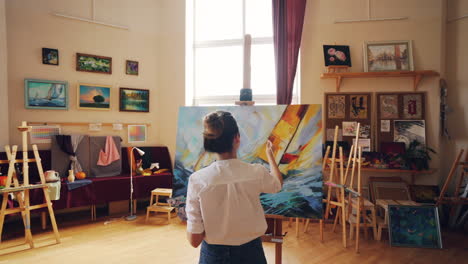 artist painting a colorful sailboat in an art studio
