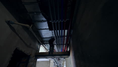 diverse electricity and ventilation pipes on the ceiling of the long corridor. low angle view. interior of the constructed building.