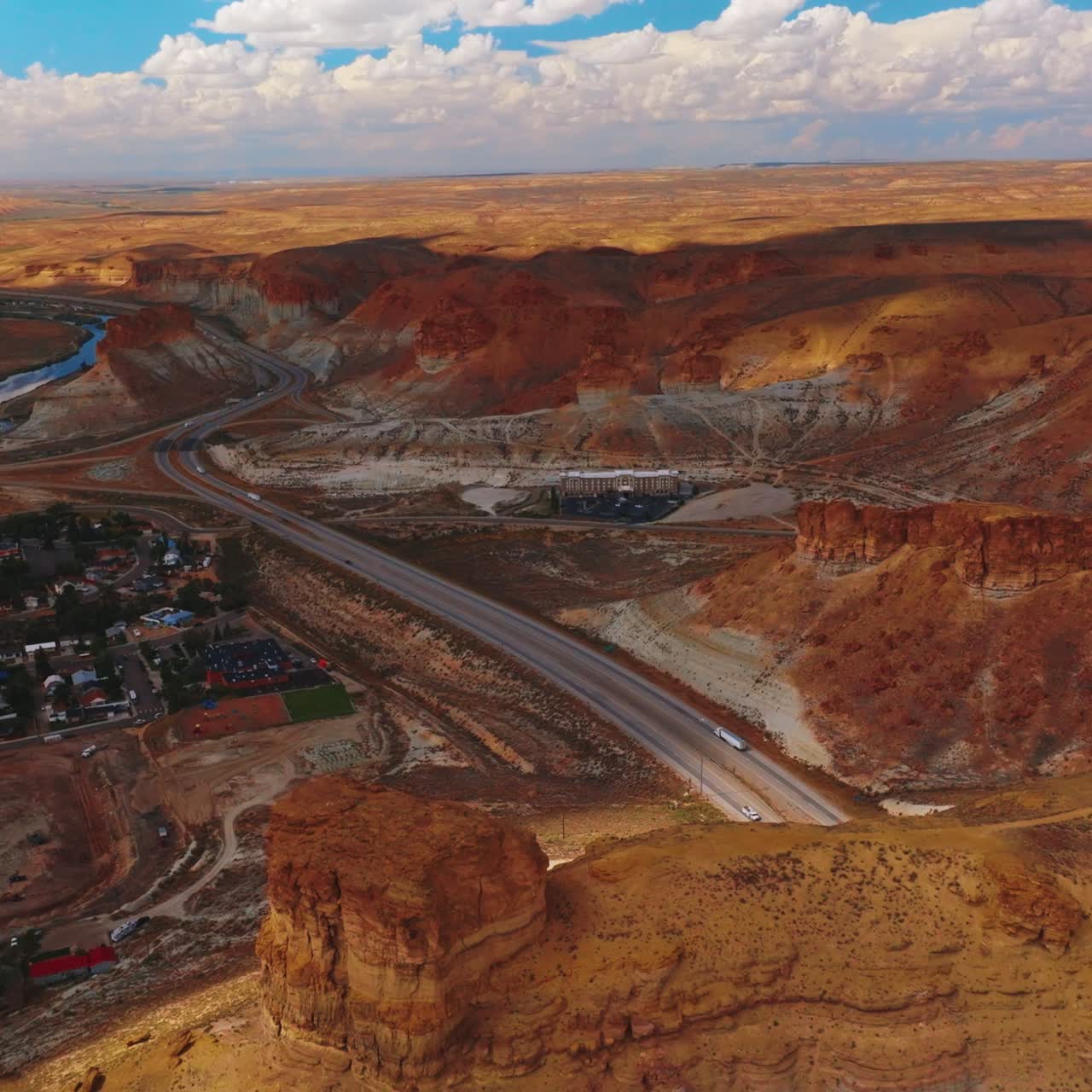 Cozy city surrounded by the bare yellow rocks. Highway through the desert in the mountains. Cloudy sky at backdrop