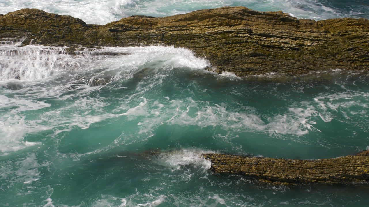 olas rompiendo a través de rocas marinas acercándose a la orilla