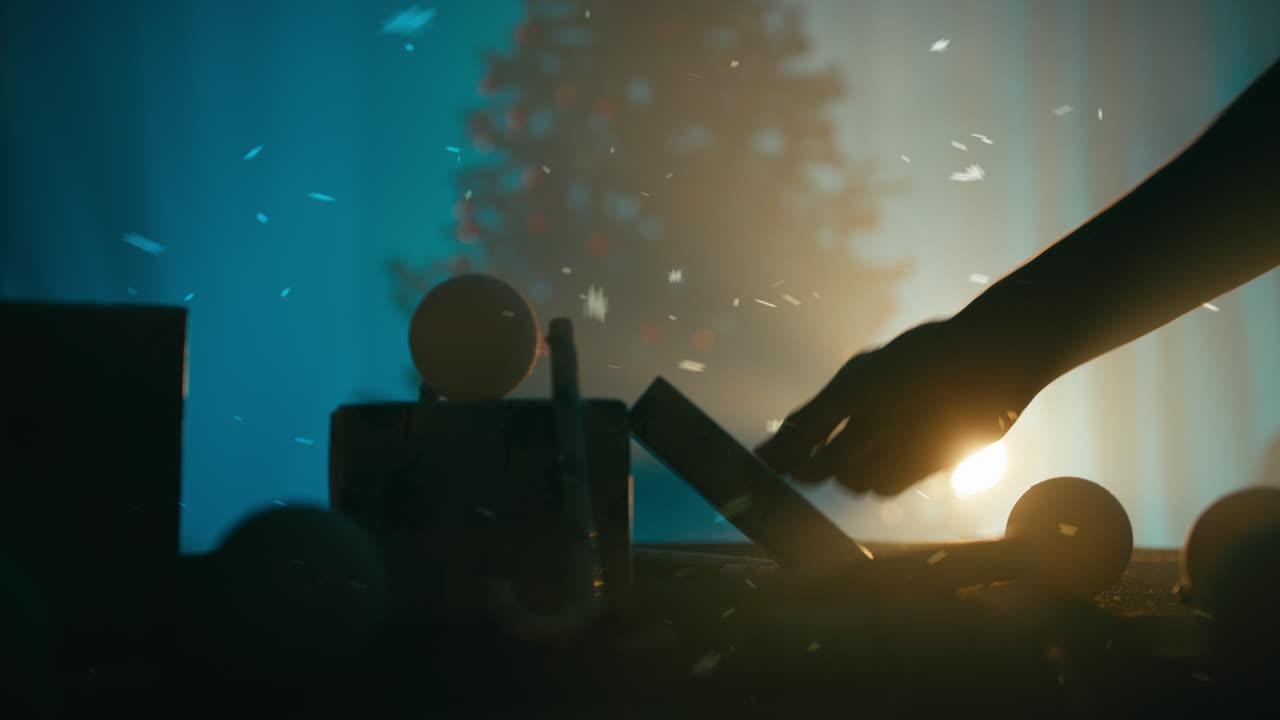Silhouette of a man's hands arranging Christmas presents at night