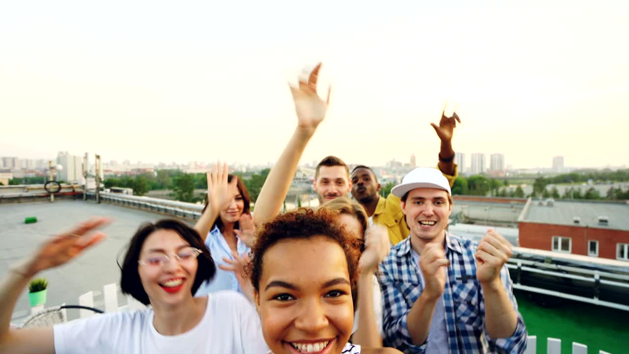 아프리카계 미국인 소녀가 친구들과 함께 옥상 파티에서 카메라를 보고 춤을 추고 재미있게 찍은 포인트 오브 뷰.