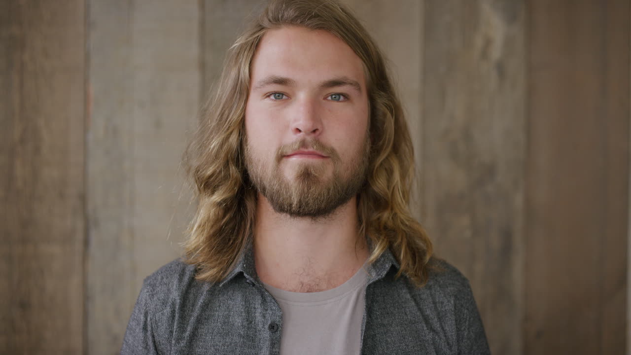 portrait of attractive young blonde man looking at camera with long hair handsome bearded male slow motion