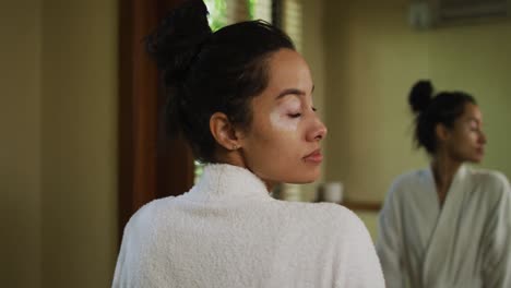 relaxed biracial woman looking at herself in mirror and smiling