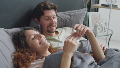 en la cama, usando un teléfono pareja