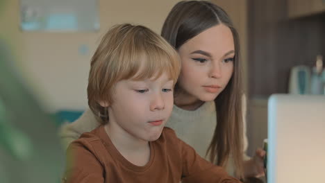 little boy and older sister watching laptop at home