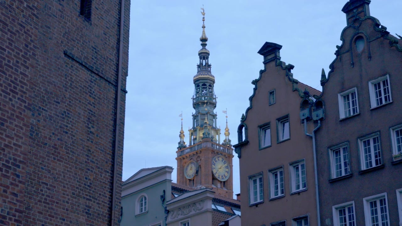 Famosa torre dell'orologio della stazione ferroviaria principale nel centro città di Danzica, Polonia, vista tra gli edifici, inquadratura di ambientazione con dettagli esterni