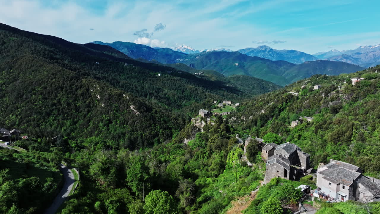 Aerial drone shot over the green lush landscape of inland Corsica, France. High view of the landscape and the mountains in the distance. Summer holidays destination for hikers and mountain lovers