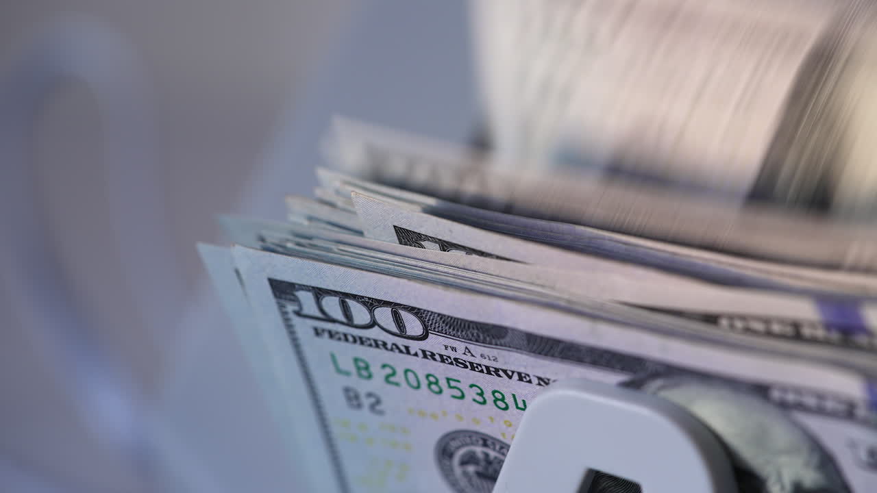 American currency hundred dollar bills falling on the holder of device. Close up. Money in cash counter machine.