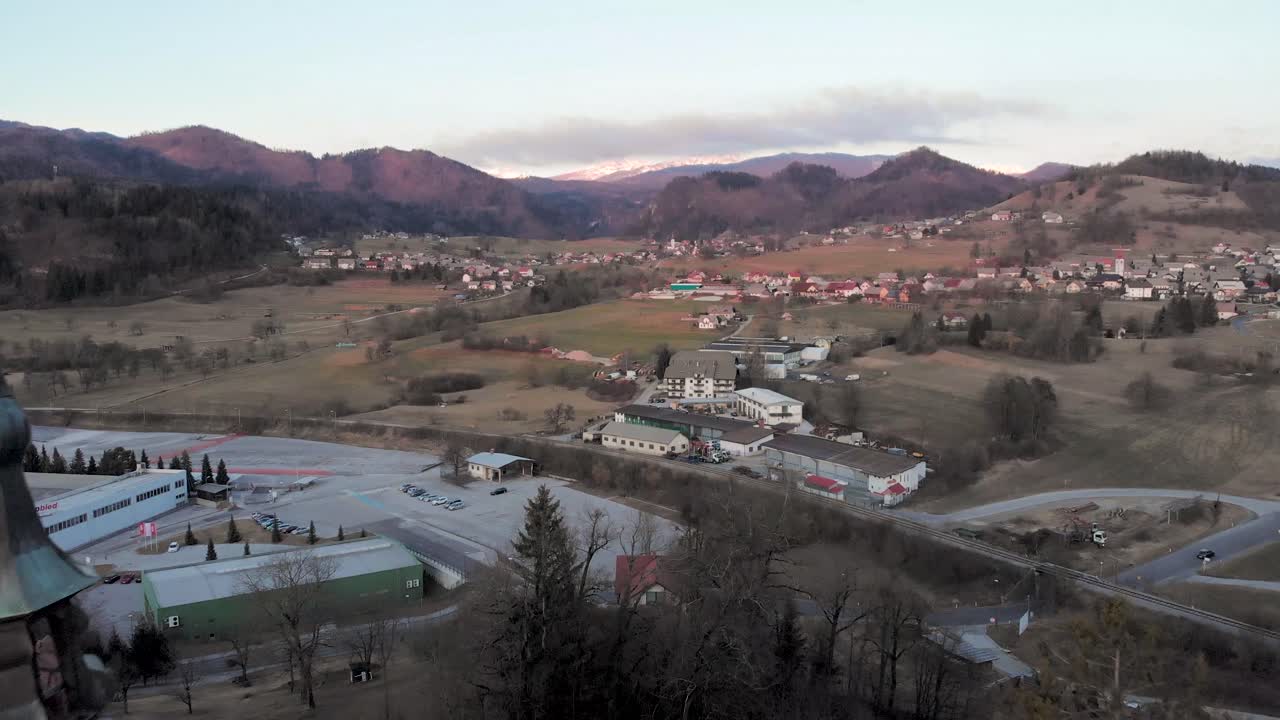 Gün doğumunda Slovenya'daki bir kilisenin üzerinden uçan drone. Arka planda dağ köyü ve Julian Alpleri.