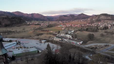 camera flying straight over the church. mountain village in the background and the julian alps of slovenia. drone flying over a slovenian church at sunrise.