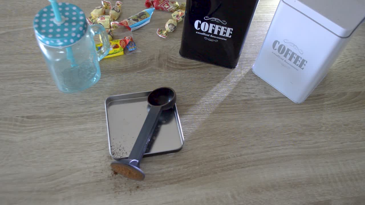 toma fija de la mano de un hombre tomando una taza de café negro de la mesa con dulces y recipientes de café